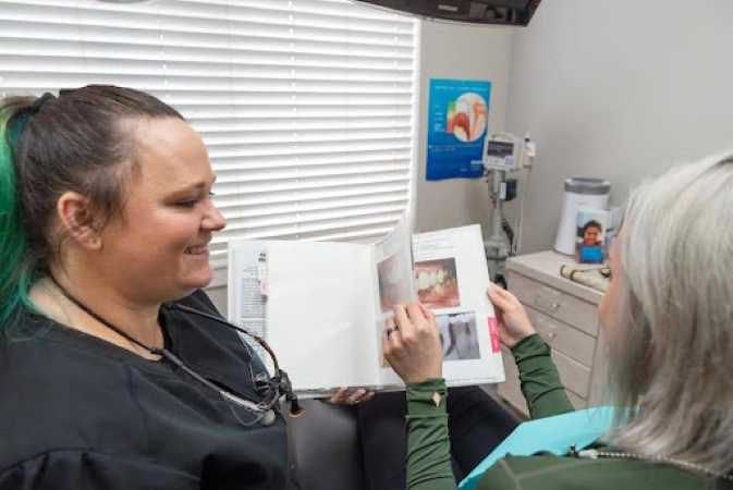 Dental professional showing dental implant photos to patient